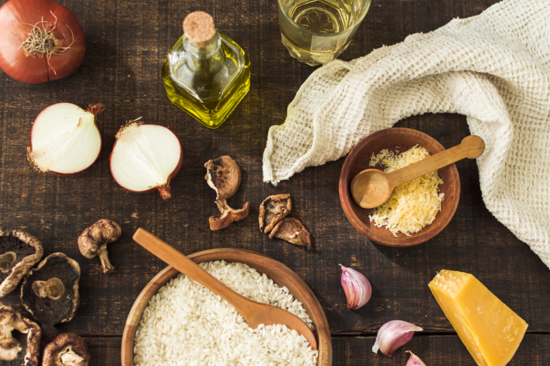 an overhead view of traditional italian risotto ingredients on wooden table